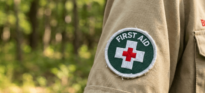 Boy Scout uniform sleeve showing first aid badge and American flag patch